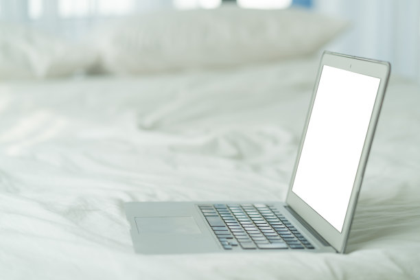周末早上，白色的床上放着笔记本电脑的空白屏幕，白天和白色的窗户图片下载