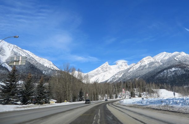 在一个阳光明媚、阳光明媚的日子里，一辆汽车在高速公路上行驶，穿过落基山脉图片下载