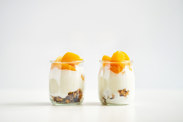 位置对称的希腊酸奶罐与格兰诺拉麦片和杏罐头在白色的背景图片下载