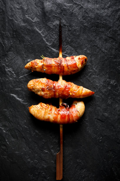烤串的鸡里脊肉裹上熏肉在背后的石头背景图片下载