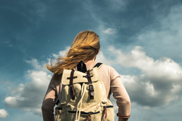 背包女在欣赏戏剧性的天空和云彩。图片下载