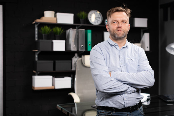 年轻人站在电脑桌附近，双手交叉放在胸前图片下载