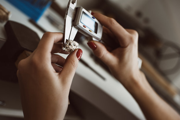 定位精度。近距离照片的女性珠宝商的手测量戒指与工具在车间。图片下载