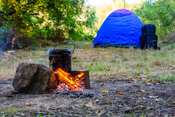 用水壶在篝火上煮食物。帐篷的背景图片下载