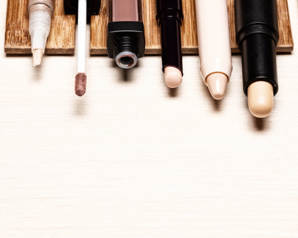 浅色木桌上有各种化妆遮瑕膏。化妆校正图片下载