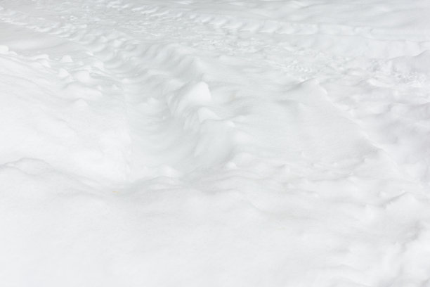 新鲜的白雪和拖拉机留下的痕迹。抽象背景与雪的纹理。图片的布局。图片下载