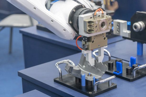 机械手臂将金属冲压件送到生产线上。图片下载