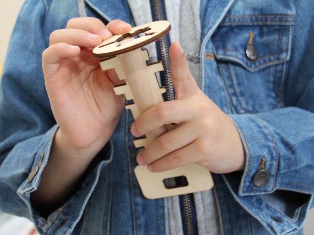 那个男孩手里拿着一个木制玩具。木制钥匙和钥匙孔。图片下载