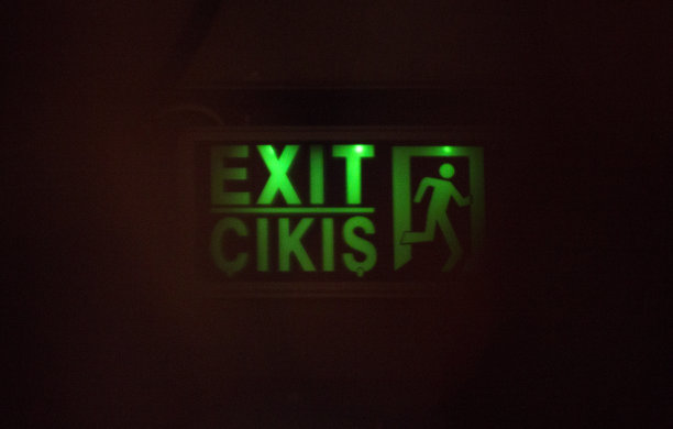 在雾蒙蒙的内部，可以看到英语和土耳其语的绿色出口标志。危险的概念，出口，绿色的走。图片下载