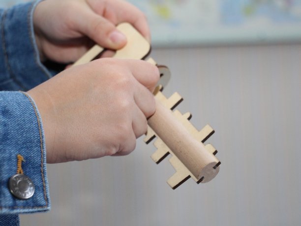 那个男孩手里拿着一个木制玩具。木制钥匙和钥匙孔。图片下载