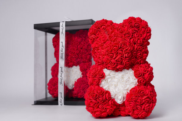 泡沫玫瑰红色泰迪熊。同样的泰迪在清楚的盒子与黑色纸封面上的背景。白色的心在泰迪爪子。股票照片孤立的白色背景。图片下载
