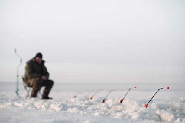 冬季钓鱼。把注意力集中在钓竿上。渔夫坐在后面图片下载