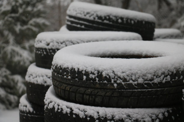用新轮胎在结冰的街道上行驶的安全性。黑色的橡胶轮胎与白色的雪形成对比。自然背景。图片下载