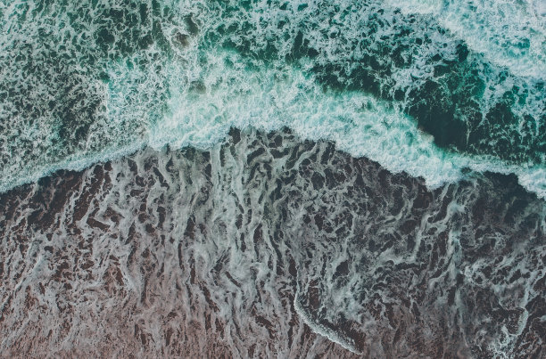 鸟瞰图海浪与泡沫在沙滩上。无人驾驶飞机的照片图片下载