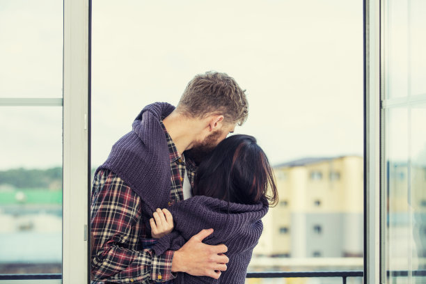 年轻的美丽和幸福的夫妇，在城市屋顶的背景下，在阳台上微笑和拥抱图片下载