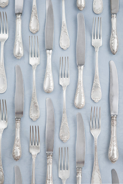 在蓝色桌布背景上放着银器、刀叉。表设置。模式图片下载