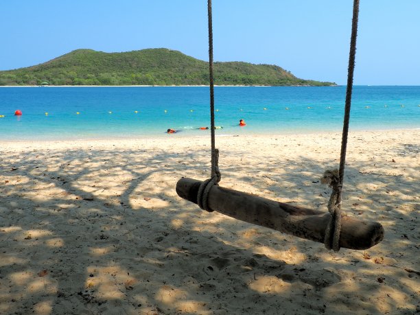 海滩与海，山，沙，和秋千在阳光照片。旅行者在海洋中愉快地度假。它是泰国春武里省的Samae San岛。图片下载