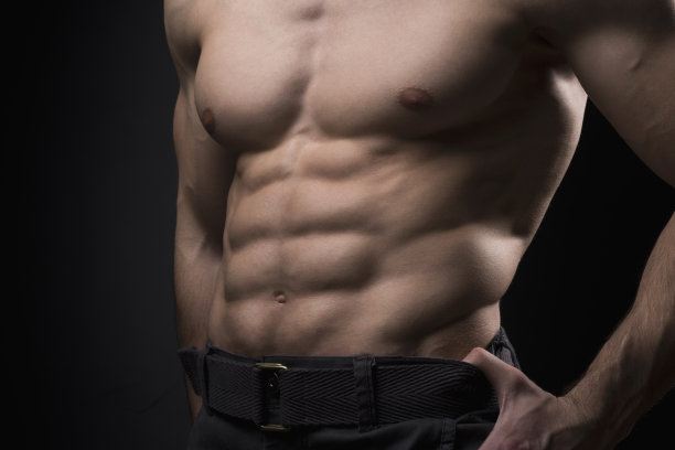 肌肉发达的年轻人在黑色背景。健身男展示六块腹肌图片下载