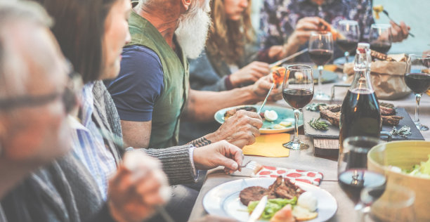 快乐的家庭吃和喝葡萄酒在户外烧烤晚餐-多种族成熟和年轻人有乐趣的烧烤周日餐-食物和夏季生活方式概念-关注潮人的手图片下载