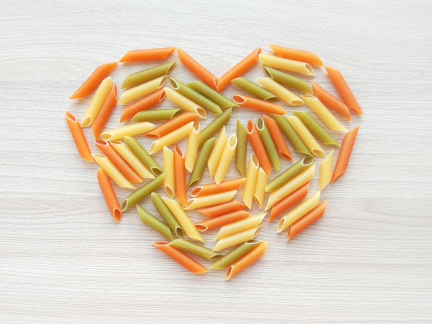 质感的意大利食物背景-彩色的生意面心形状的木桌图片下载