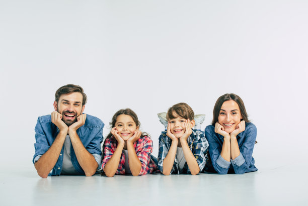 近距离的照片微笑美丽的现代家庭躺在地板上，看着相机图片下载