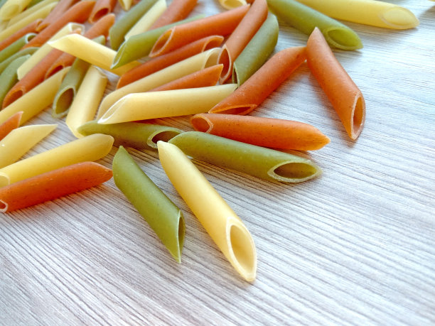 质感的意大利食物背景-彩色的生通心粉在木桌上图片下载