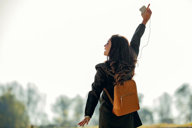 无忧无虑的女人举起手臂在公园里玩。图片下载