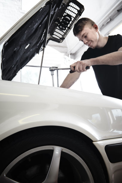 一个年轻的机械师在一辆白色汽车上工作图片下载