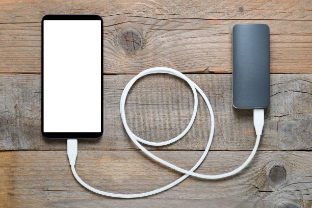 木制背景的电源和智能手机素材图片