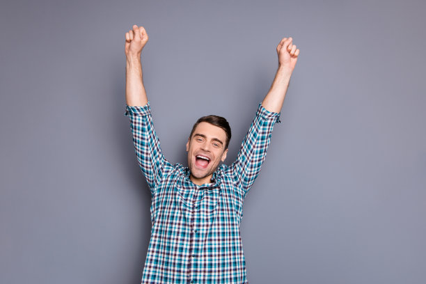 近距离的照片令人惊讶，他他的男人双手举起显示理想的完美发型，强壮的肩膀，球迷穿着休闲格纹格子装孤立的灰色背景图片下载