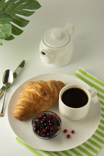 早餐，咖啡和牛角面包和浆果果酱在白色的桌子上。法国的羊角面包。新鲜的小面包，小吃。与拷贝空间隔离。点心和甜点。图片下载