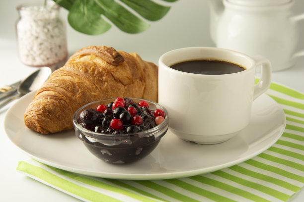 早餐，咖啡和牛角面包和浆果果酱在白色的桌子上。法国的羊角面包。新鲜的小面包，小吃。与拷贝空间隔离。点心和甜点。图片下载
