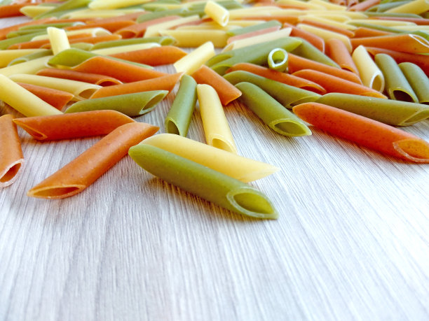 意大利食物——木桌上五颜六色的生通心粉图片下载
