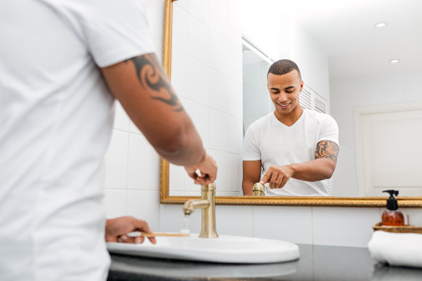 年轻的帅小伙用水清洗他的竹牙刷图片下载