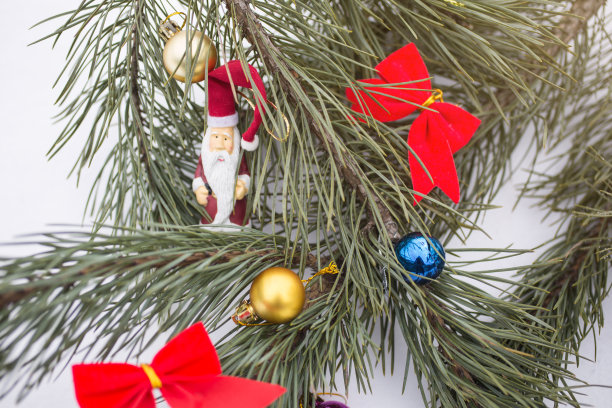 玩具圣诞老人和红色的蝴蝶结挂在圣诞树上。冰冻森林中的自然照片。节日快乐的明信片。新年的装饰品装饰。下雪的天气。图片下载