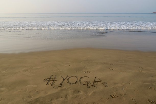 图片的标签标签写在阳光明媚的海滩上，瑜伽词写在海边的沙子，帕洛伦海滩，印度果阿，概念社交媒体照片的手写在金色的沙子与现代标签前缀图片下载