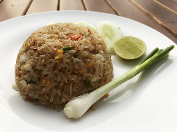 木桌上的白盘螃蟹炒饭，泰国美食，泰国菜单的名字是:“Kao pad poo”。图片下载