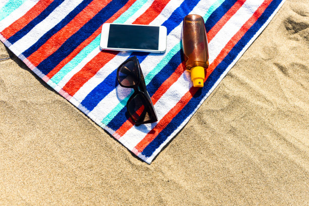 沙滩毛巾，手机和防晒霜图片下载