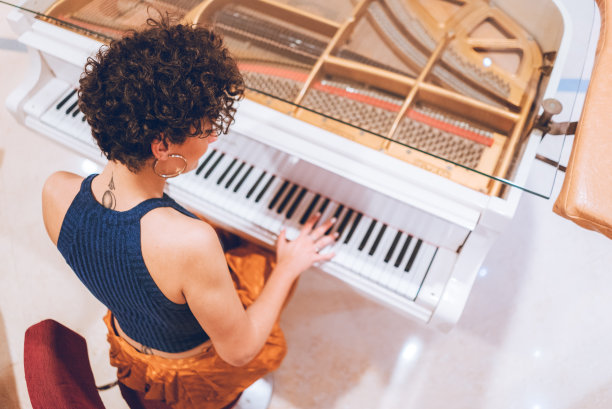 美丽的年轻女子弹钢琴图片下载