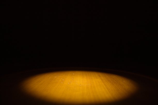 一个大聚光灯在木地板或桌子上的浅景深的现场照片和黑暗的周围图片下载