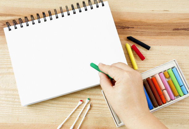 女人手持油彩粉笔艺术挑选艺术绘画在纸上和彩色蜡笔在木桌背景与文本复制空间集盒。图片下载