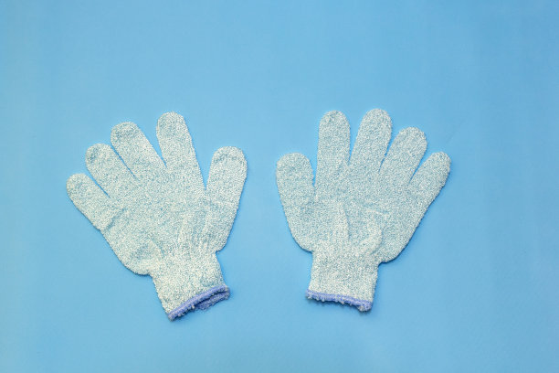 沐浴按摩蓝色手套与去角质水剥落磨砂效果柔软的蓝色背景。俯视图，平放图片下载