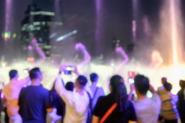 模糊的场景，人们看激光表演与喷泉活动图片下载