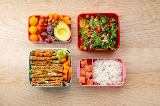 创意的布局，健康的午餐菜肴，各种各样的便当盒放在木桌上。三明治，沙拉配谷物和石榴籽，鲑鱼配米饭和水果点心。日常办公室或学校午餐的概念图片下载