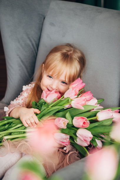 兴高采烈的女孩捧着一大束花坐在椅子上。郁金香,图片下载