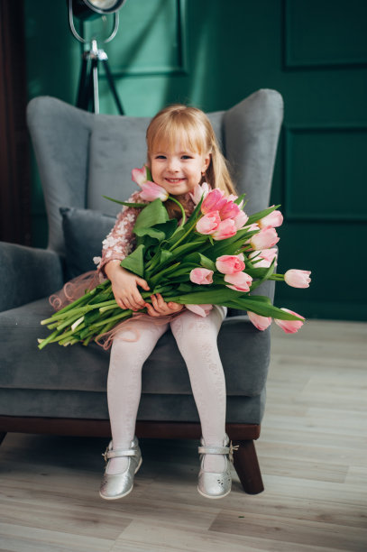 兴高采烈的女孩捧着一大束花坐在椅子上。郁金香,图片下载