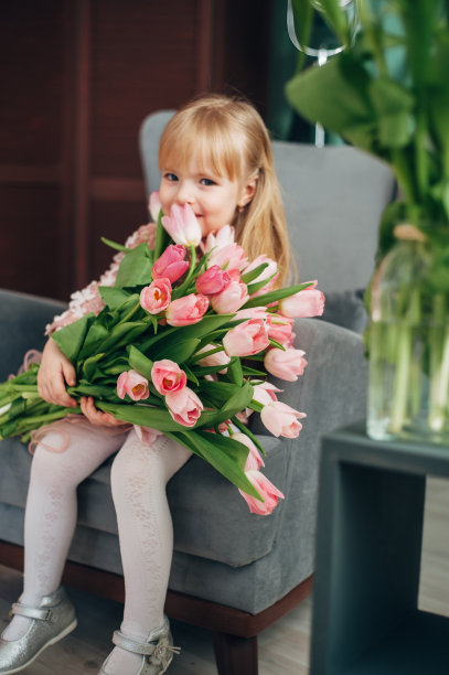 兴高采烈的女孩捧着一大束花坐在椅子上。郁金香,图片下载