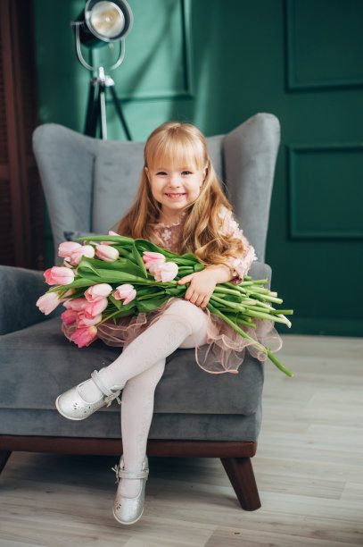 兴高采烈的女孩捧着一大束花坐在椅子上。郁金香,图片下载