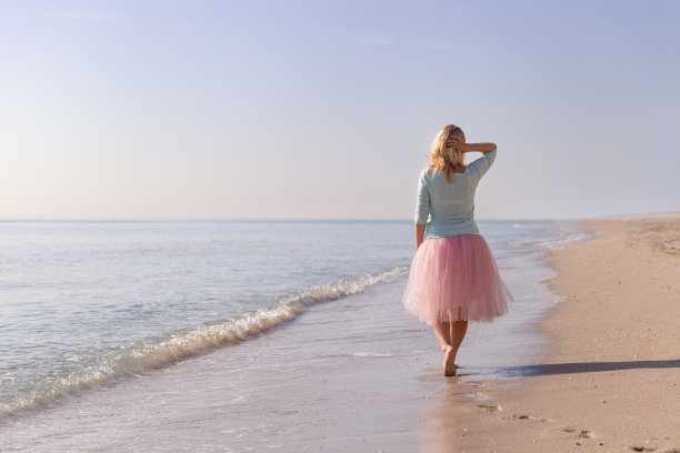 美丽的年轻女子走在沙滩上。夏季假期。沙滩上微笑的女孩。快乐的女人享受假期。图片下载