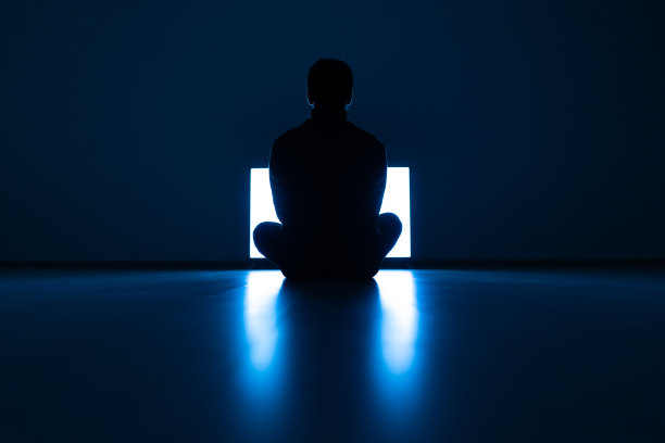 在黑暗的房间里，男性坐在电视机前的地板上图片下载